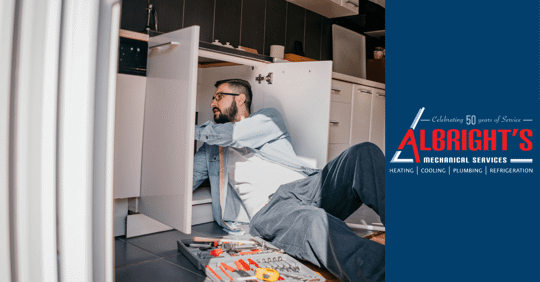 man fixing pipes under sink