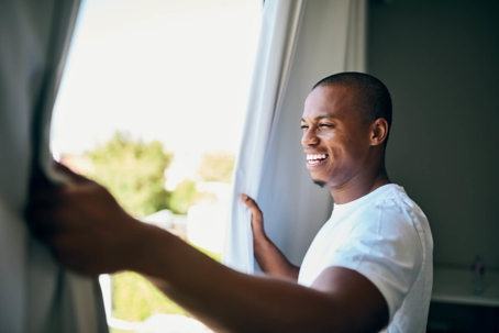 young man looking out of bright window